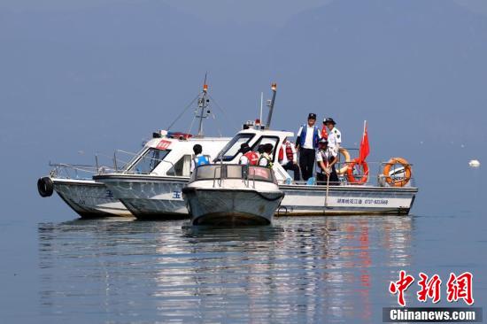 工作人员乘船打捞湖中的水下地笼、虾笼。