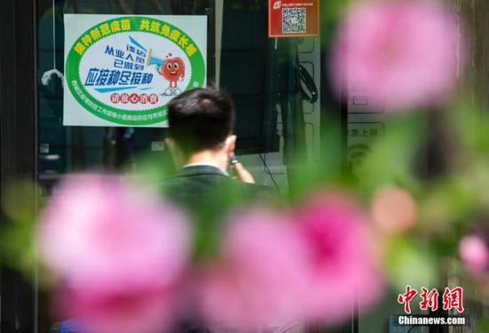 4月6日,北京市西城区金融街的一处商铺入口处张贴有新冠疫苗接种绿色标识。中新社记者 侯宇 摄