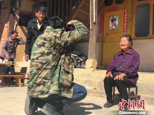 图为杨董清向村民展示拍摄的照片 杨钏杰 摄