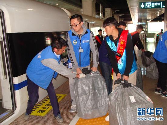 青年志愿者和搬运人员正将包裹搬运到动车内。(供图)