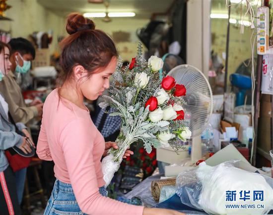 2月14日,在泰国曼谷帕空鲜花市场的一家花店,工作人员将从云南进口的鲜花制作成花束和花盒。 新华社记者 张可任 摄