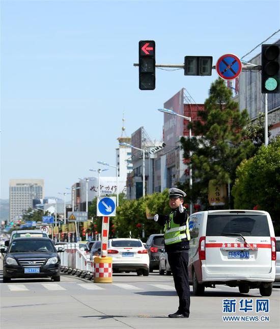 5月1日,交警在山东省枣庄市文化路指挥交通。 当日是“五一”小长假第一天,各行各业都有依然忙于劳动的身影。 新华社发(孙中喆 摄)