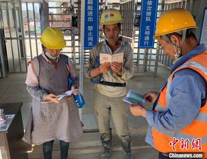 图为农民工阅读《保障农民工工资支付条例》宣传册。 孙洋洋 摄