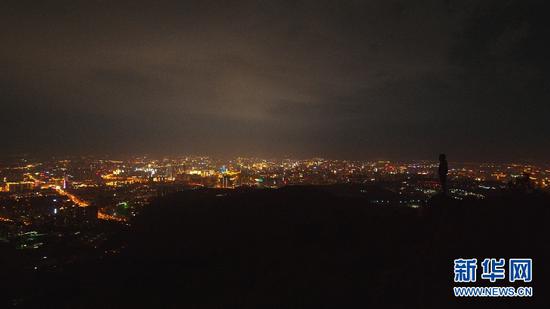 9月3日,站在长虫山顶岩石上观看城市夜景的游客。(新华网 刘东 摄)