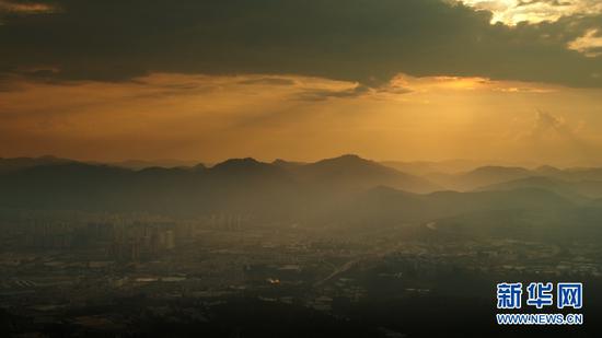 9月3日,夕阳下的城市一角与群山。(新华网 刘东 摄)