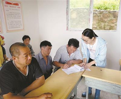 2018年8月,王秋婷(右一)和驻村干部在大湾村民小组召开群众会,对新纳入贫困户进行评定,确保扶贫工作公平、公开、公正。(资料图片)