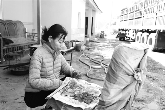 祥临公路旁的小小加水站里,丈夫忙着洗车加水,罗芹美蹲在旁边绣十字绣。