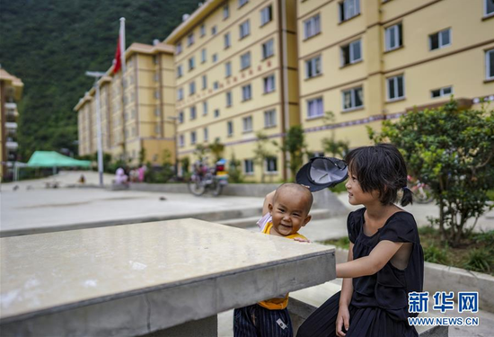 在云南怒江傈僳族自治州泸水市大龙塘易地扶贫搬迁安置点,6岁的麻医平(右)带着弟弟在院子里玩耍(9月15日摄) 。新华社记者 江文耀 摄