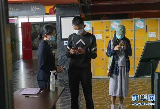 7月20日,在昆明市北辰财富中心影院入口处,工作人员指导观众填写防疫信息。新华社发(陈欣波 摄)