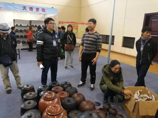 县文产办主任、县紫陶产业发展中心主任童石磊到参展企业杨庆祥陶艺坊了解情况