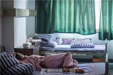 一位患者躺在病房里的床上休息,红色的病号服,表明她属于“一级护理”对象。