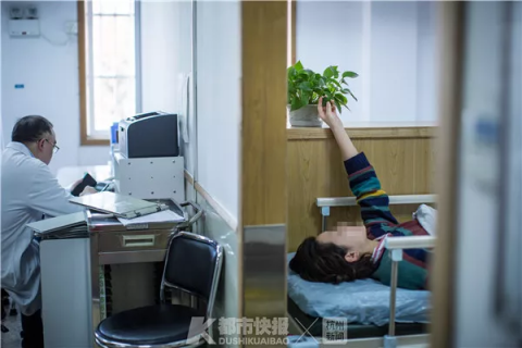 一位患者在等待治疗时,伸手触摸桌上的绿植。