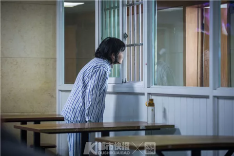 一位患者透过病区的窗户,朝对面的医生办公室张望。