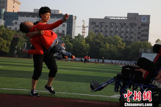 儿子“走”一圈累了,施爱英再把儿子抱上轮椅推回家。 吴建勋 摄