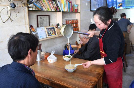 图为:早餐店老板娘正在为顾客冲泡豆浆。 王刚 摄