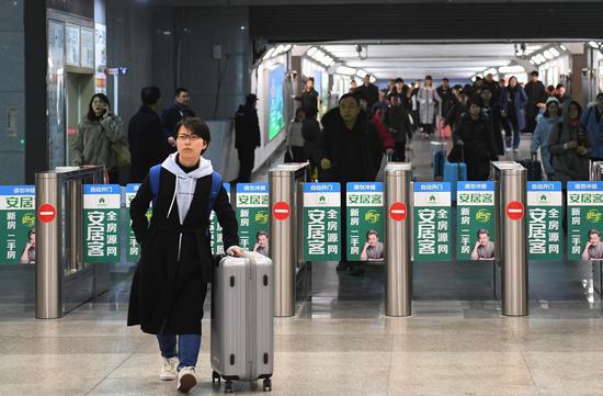 图为:一位旅客走出火车站。 王刚 摄