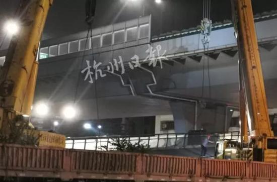 两台吊机分别用吊绳固定住断裂桥体两侧,将其缓缓拉起,并放置于拖车上。