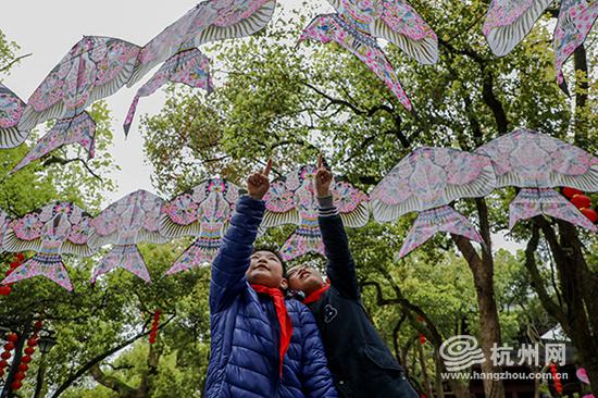 两位小朋友兴奋地讨论着最喜欢的一只燕子风筝。