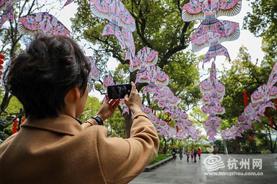 一位春游带队老师看到同学们在风筝下嬉戏用手机记录下美好的时刻。