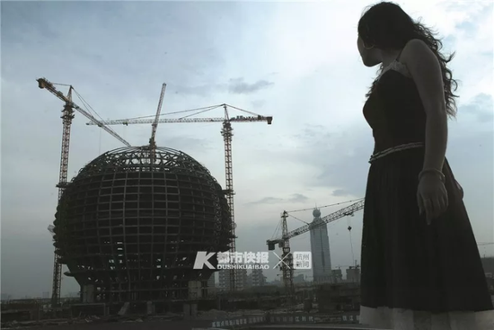 2007年8月26日,一位陕西在杭打工的姑娘在杭州大剧院前拍照,背景是建设中的杭州国际会议中心。李建刚 摄