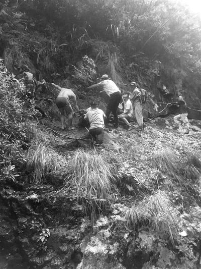 救援队员艰难地把伤员抬下山