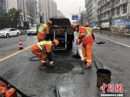环卫工人修补雨天侵蚀的沥青路面。 西湖区城管局提供 摄