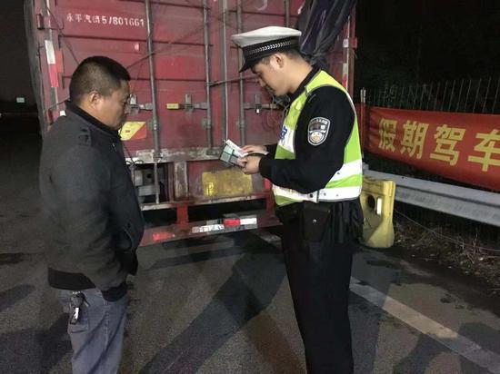 图为:交警正在核对驾驶员身份。高速交警总队湖州支队