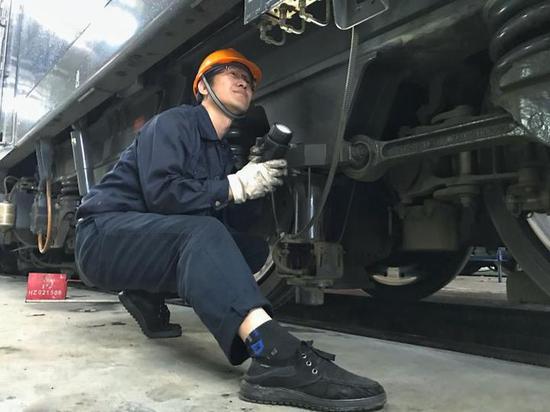 (中国铁路上海局集团有限公司杭州机务段检修工程师正在对春运代客机车走行部进行仔细检查,确保机车质量稳定可靠)