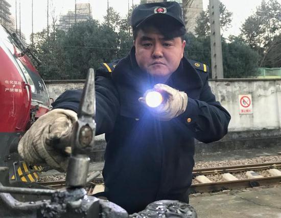 (中国铁路上海局集团有限公司杭州机务段机车司机正在对即将出库的机车车钩进行状态检查,确保机车与客车车厢连接安全)
