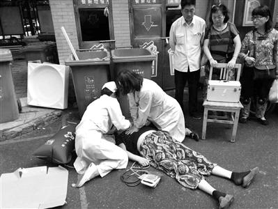 满医生跪在地上给大妈急救 图片由小区居民拍摄