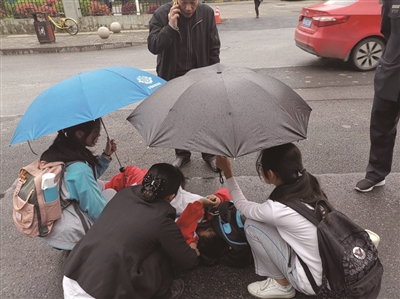 风华中学两位女生帮倒地男孩撑伞 学校供图