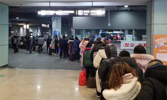 图为:杭州高铁站,等待公交的旅客排起近百米长队。 王刚 摄