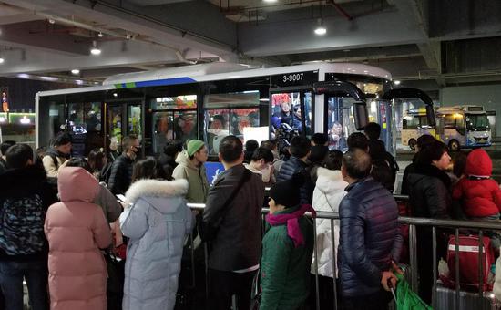 图为:众多旅客挤满中转公交站台。 王刚 摄