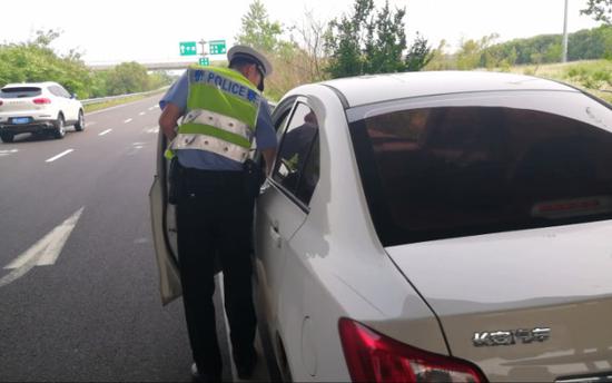 梁警官敲门将驾驶座上的男子叫醒,并示意他出示驾驶证和行驶证。