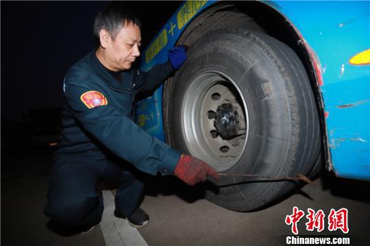 图为吴益君检查轮胎是否正常。 董美巧 摄