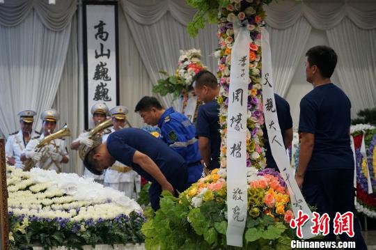 参与吊唁的人员向周锦勇献花并鞠躬致敬。 婷玮 摄