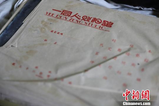 玻璃底片外的包装纸上印着“一同人照相馆”字样。 王哲能 摄