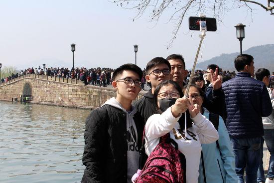 图为:游客们在西湖边自拍留念。 柱子 摄