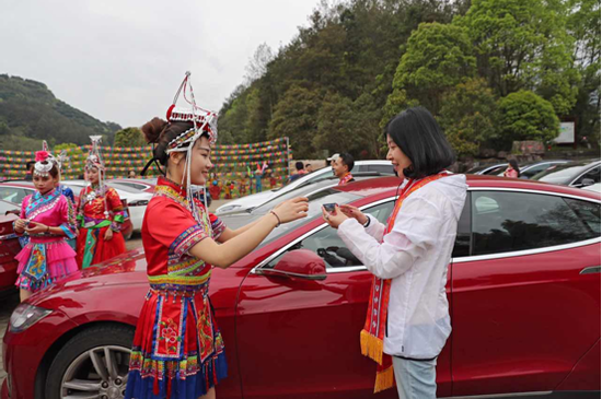 在东西岩景区,畲族姑娘与特斯拉车队热情互动