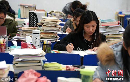 12月7日,郑州大学新校区,考研进入倒计时,记者探访高校“考研族”。图为课桌上,堆满复习资料。马健 摄 图片来源:视觉中国