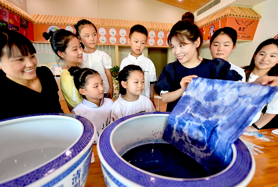 在亳州市林拥城景区书香药都美学馆,志愿者在向小朋友传授扎染的制作