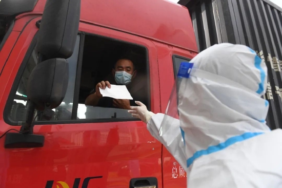 11月24日，在合肥绕城高速集贤路道口，余银伟为大货车司机送上N95口罩。全媒体记者 郭如琦 摄