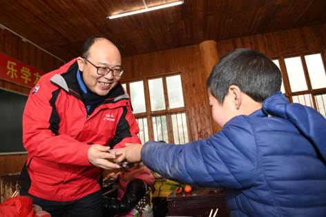 广汽三菱副总经理向毅给大托希望小学的小朋友递腊八粥