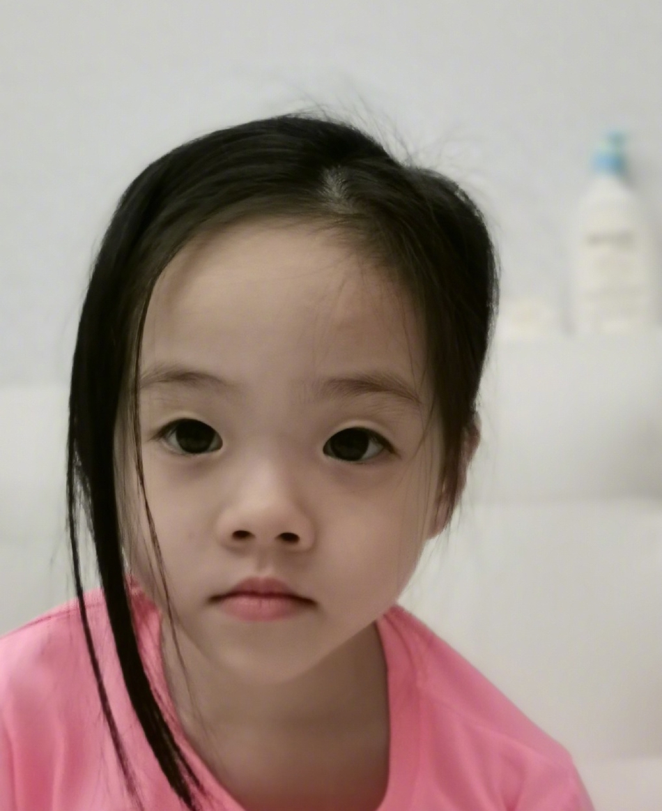 照片中欢欢乐乐穿着同款粉色小裙子,手里拿着棒棒糖,可爱俏皮.