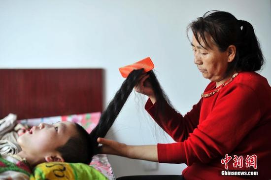 在山西省大同市南郊区马军营乡一栋回迁楼内，54岁的赵玉春将馒头嚼碎后，嘴对嘴喂到女儿口中，像哺育幼鸟一般。这样把食物嚼碎喂到女儿嘴里的动作，赵玉春与妻子李焕梅重复了15年。从弃婴到少女，这个抱养回家的脑瘫女儿就这样被一口一口喂养长大。养母患癌症割舍不下女儿。