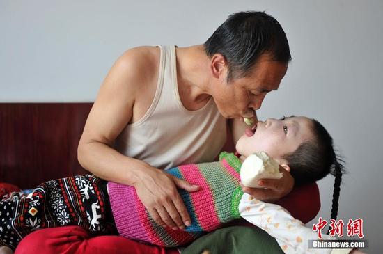 在山西省大同市南郊区马军营乡一栋回迁楼内，54岁的赵玉春将馒头嚼碎后，嘴对嘴喂到女儿口中，像哺育幼鸟一般。这样把食物嚼碎喂到女儿嘴里的动作，赵玉春与妻子李焕梅重复了15年。从弃婴到少女，这个抱养回家的脑瘫女儿就这样被一口一口喂养长大。养母患癌症割舍不下女儿。