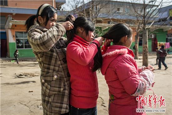 河南省安阳市安阳县,一家留守儿童托管班中,3名女孩在扎辫子
