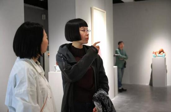 展览艺术家丁荭(右一)与艺术家米玉明交流