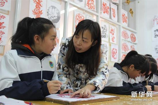 12月7日，河北省临西县第一中学教师在课堂上指导孩子进行剪纸。