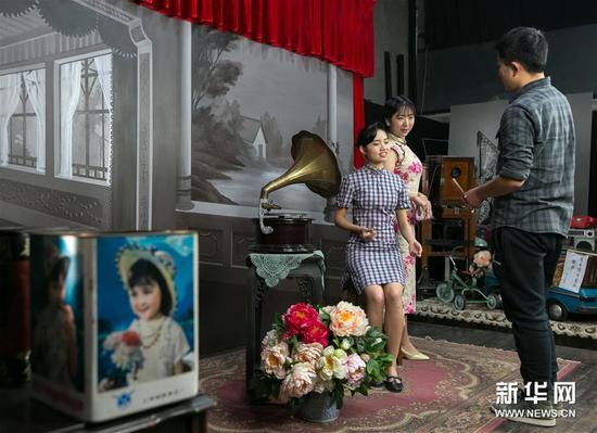 在白夜照相馆内，白夜照相馆的工作人员为顾客演示拿扇子的动作（1月10日摄）。